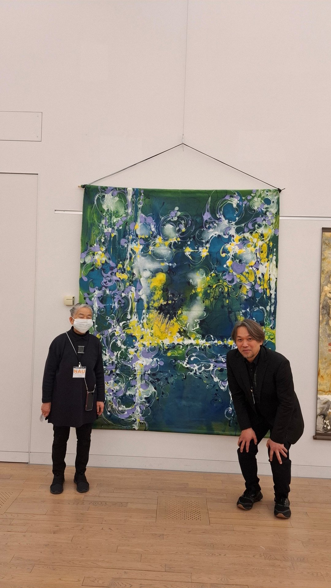 日本第二十三《NAU21世紀美術連立展》-東京國立新美術館展覽-ichonokigallery社長、藝術家 加藤和美女士與台灣參展者 王穆提先生(日本NAU21世紀美術連立展成員)於台灣參展者 李元慶先生作品前合影。